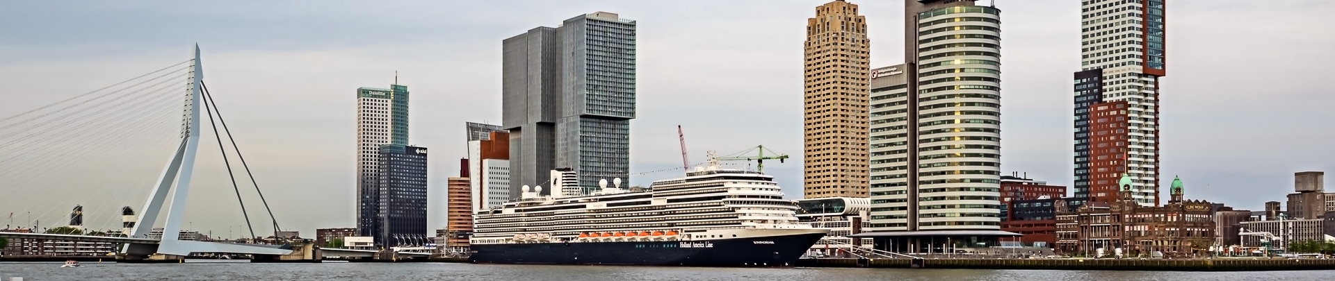 De erasmusbrug van Rotterdam met enkele gebouwen, water en een boot